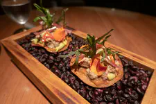Alpaca, nasturtium flower, papadum, it's being served on a bed of blue corn kernels (ckolli).