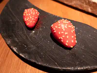 Amuse of candy shell filled with strawberry pulp and wasabi.