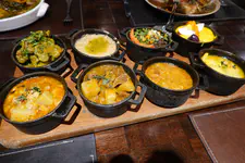 Eight classic creole dishes samples for sharing and celebrate: mollejitas a la limeña (chicken gizzards), ají de gallina (chicken in yellow chile sauce), carapulcra (pork and dried potato stew), cau cau (tripe and potato stew), sangrecita (blood pudding), patita con maní (pork leg with peanuts), chanfainita (beef lungs), beans with seco sauce, and rice.